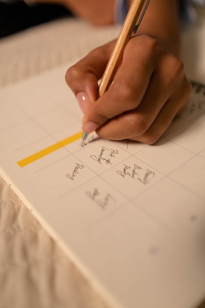 A close-up of a hand writing notes in a planner, emphasizing planning and organization.